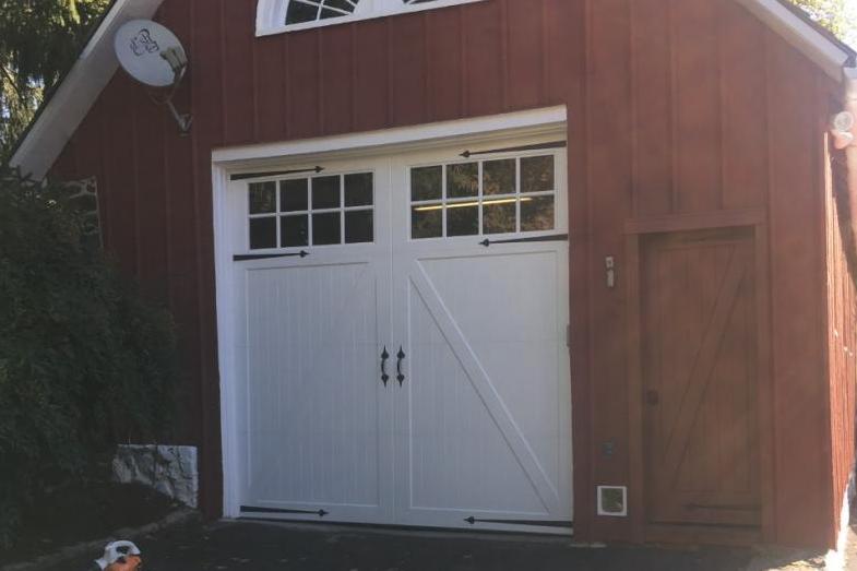 An extra tall carriage house overlay style door on a red barn/garage.